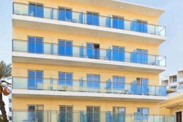 Prednja fasada Hotela Africa u Rodosu u Grčkoj. Žuta fasda, staklena ograda, prozori, vrata.
