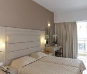 Jedna od soba Hotela Africa u Rodosu u Grčkoj. Namšteni kreveti, osunčana soba, stolica, ogledalo, sto, TV, klima, cvece, telefon.